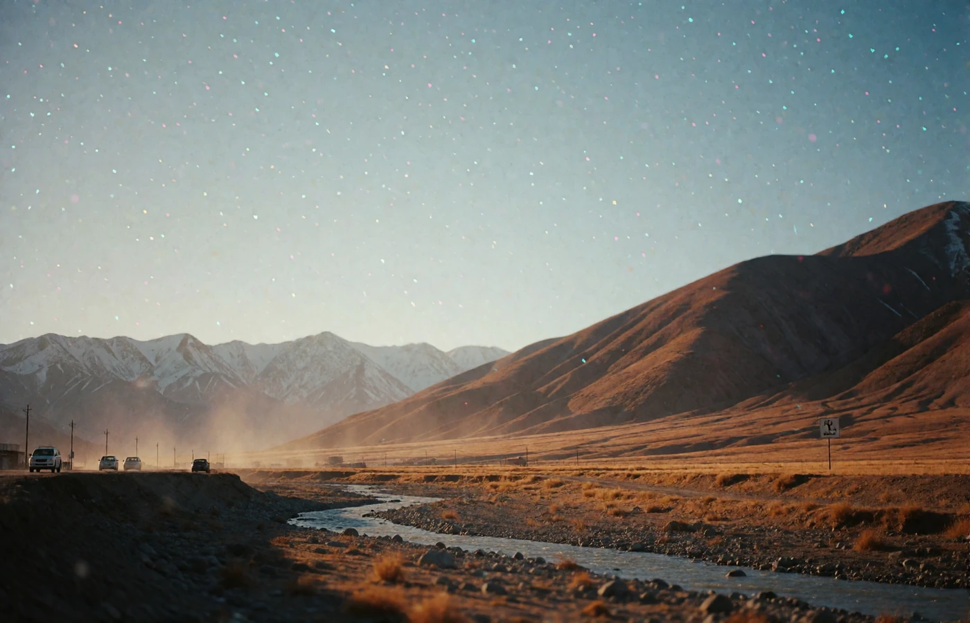 Arid highland plateau in Afghanistan at golden hour with ochre mountain slopes and a dry riverbed