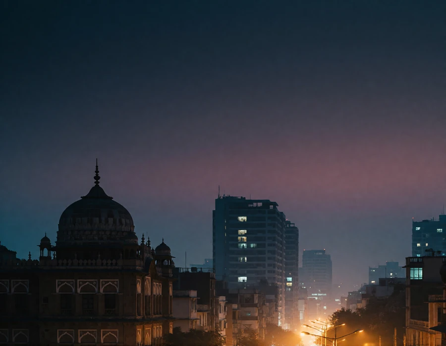 Dusk skyline of an Indian city with a heritage domed building silhouetted against modern towers and a warm indigo sky