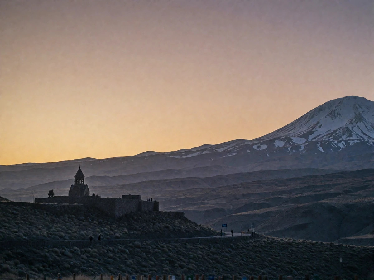 Wide view of the Armenian highlands at dusk with layered volcanic ridges and a distant snow-touched peak